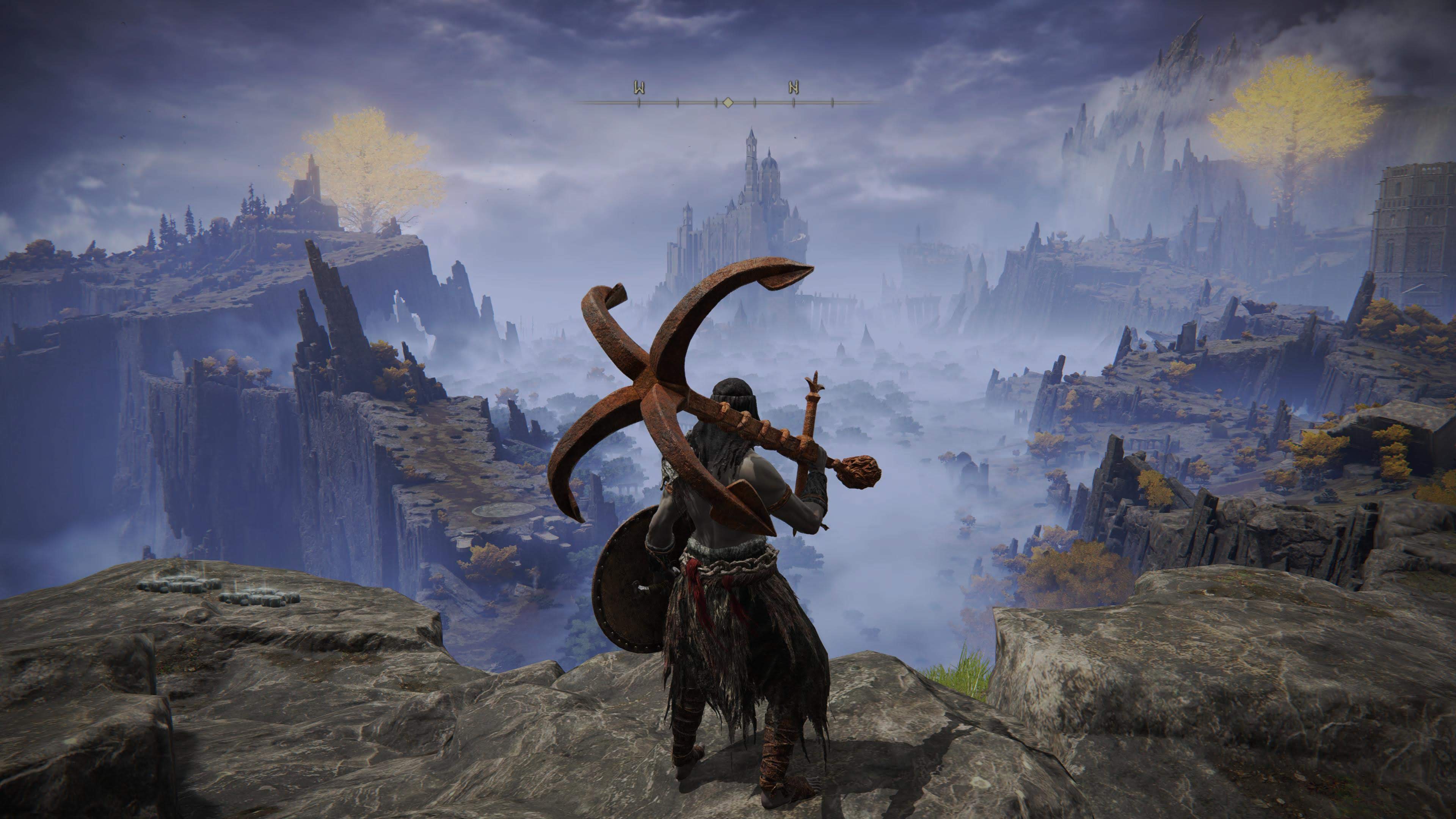 A player at the edge of a cliff overlooking a brilliantly lit foggy landscape of Elden Ring.