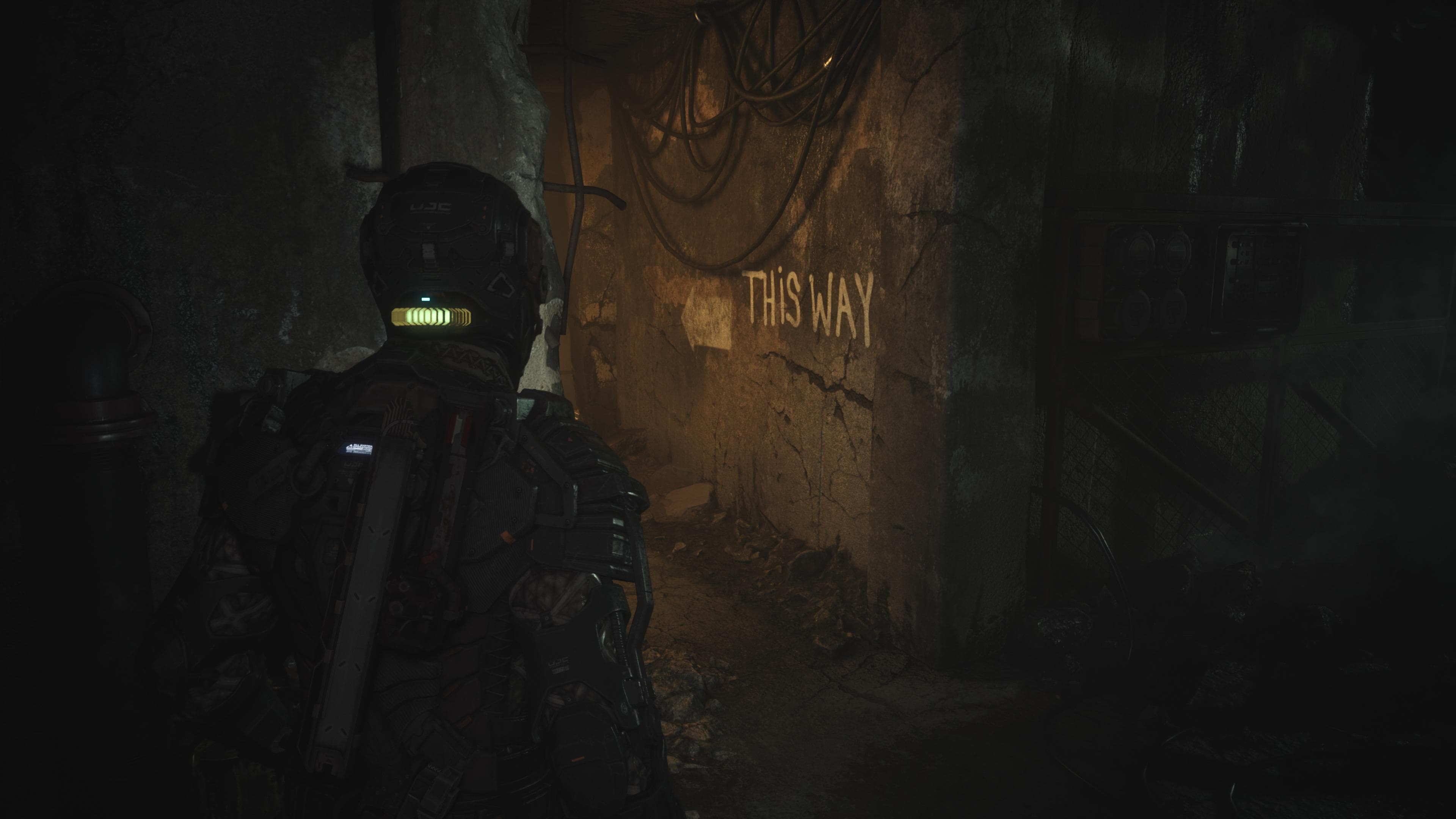 Jacob continues down a dark corridor, noticing a sign on the wall which reads "THIS WAY"